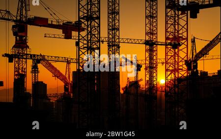 Baustelle und Bau Kräne auf Sonnenuntergang Himmel in der Stadt Stockfoto