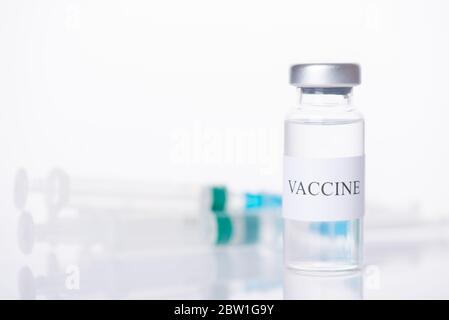 Konzept der Impfstoffbehandlung. Nahaufnahme von Impfstoff Fläschchen und verschwommene Aufnahme hinter isoliert auf weißem Hintergrund Stockfoto