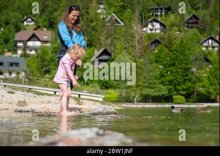 Mutter und Tochter erkunden Seeufer im Sommer. Stockfoto