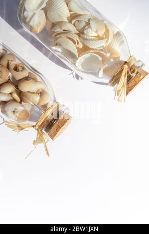 Zwei diagonale Glasflaschen gefüllt mit Muscheln auf weißem Hintergrund Stockfoto