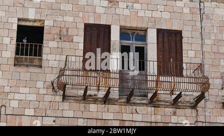 Eine Taube scheint einen gefährlichen vernachlässigten rostigen alten Eisenbalkon auf einem Kalksteingebäude in jerusalem in israel zu inspizieren Stockfoto