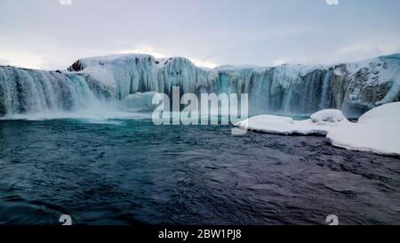 Low-Angle-Foto, wenn ein breiter Wasserfall in Nordisland. Der Wasserfall ist teilweise gefroren, aber das kalte Wasser entweicht seiner Eisdecke. Das Foto wird aufgenommen f Stockfoto