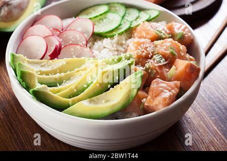 Pokerschale, traditioneller hawaianischer Rohfischsalat mit Reis, Avocado, Gurke und Rettich auf Holzhintergrund Stockfoto