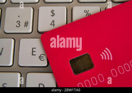 Nahaufnahme der rosa Kreditkarte auf einer Computertastatur. Euro, Dollar und Prozent. Microchip und payless. anonymus-Nummer. Konzept der Internet-Einkäufe Stockfoto