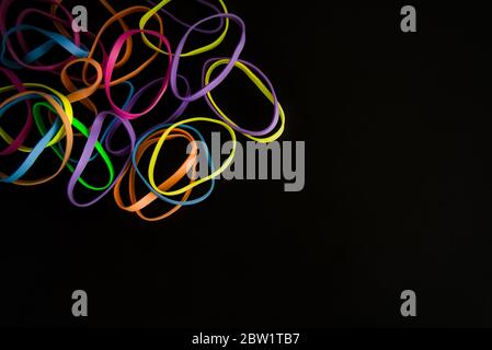 Bunte Gummibänder auf einem schwarzen Hintergrund isoliert. Minimalistisches Konzept. Hintergrund Stockfoto