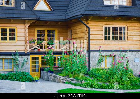 Haus des Hochlandshauses aus Holz. Pflanzen und Blumen vor dem Haus. Stockfoto