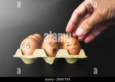 Nahaufnahme eines Dutzend Eier und eines erwachsenen Mannes Hand zu symbolisieren verschiedene Zustände von Menschen in einer Situation der Unterdrückung, erfassen, erschrecken, schleichen w Stockfoto