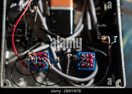 Die Kabel und Komponenten bilden eine hausgemachte Schalteinheit für Audiogeräte. In einem robusten Stahlkasten eingeschlossen. Stockfoto