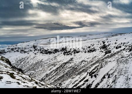 Sonne scheint durch die Wolken über den Bergen in einem Verschneite Landschaft Stockfoto