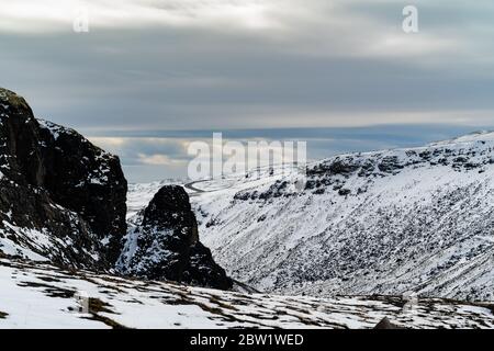 Berglandschaft mit großer Felsformation im Vordergrund, und eine Straße im Hintergrund Stockfoto