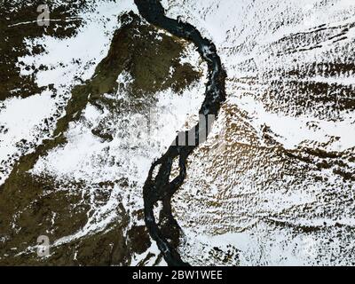 Luftaufnahme eines kleinen Baches, der durch den Schnee fließt Stockfoto