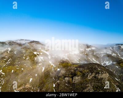 Drohne Foto von der Spitze einer Bergkette bedeckt In Wolken und von der Morgensonne beleuchtet Stockfoto