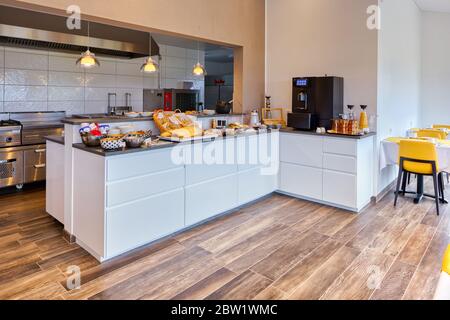 Komplettes Frühstücksbuffet in einem modernen Hotel mit frischen und hausgemachten Produkten und Kaffeemaschine. Blick auf die Industrieküche Stockfoto