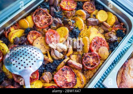 Gebackener Reis mit schwarzen Wurst Tomate in Portionen, Leiter der gesamten Knoblauch, Kartoffeln, Kichererbsen und Rippchen. Typisch valencianische Gericht. In einem Fach serviert f Stockfoto