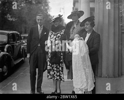 Herzogin von Kent kehrt mit ihrem Patenkind der Taufe zurück. Die Herzogin von Kent war eine Patin bei der Taufe in dieser Lambeth Palace Kapelle der Tochter von Lord und Lady Herbert. Das Baby bekam die Namen Diana Mary. Beide Eltern sind Mitglieder des Hauses des Herzogs von Kent. Lord Herbert ist dem Herzog gleichgesetzt und Lady Herbert ist eine niedrige Dame, die auf die Herzogin wartet. Foto zeigt die Herzogin von Kent, die eine Sommermode trägt, mit Lord und Lady Herbert und dem Baby bei ihrer Rückkehr in das Haus des Lord Herbert Eaton Square nach der Taufe. Juni 1937 Stockfoto