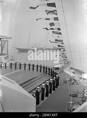 Der König bewertet Flotte bei Spithead. An Bord der königlichen Yacht, Victoria und Albert, fuhr der König durch die 5 Meilen Linie von 160 Kriegsschiffen und Handelsschiffen, als er seine Krönungsüberprüfung der britischen Marine und der Merkantile Marine in Spithead machte. Fast 300 Schiffe, darunter 17 von ausländischen Flotten, wurden überprüft. Foto zeigt, die Royal Yacht 'Victoria und Albert' vorbei an der Flugzeugträger HMS glorreichen als die Crew gekleidet Schiff. 20 Mai 1937 Stockfoto