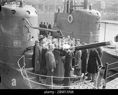 London sieht die Marine. U-Boote in Dock in der Nähe der Tower Bridge. Die U-Boote der Heimatflotte, die im Pool von London zur Krönung stationiert waren, wurden nur wenige Stunden nach ihrer Ankunft für die Besichtigung geöffnet. Fotoausstellungen: Offiziere erklären Besuchern an Bord des U-Bootes HMS Starfish (19S) im St Katharine's Dock, London, die Waffen. Ein weiteres U-Boot der Gruppe 1 der britischen S-Klasse HMS Swordfish (61S) ist im Hintergrund. Mai 1937 Stockfoto