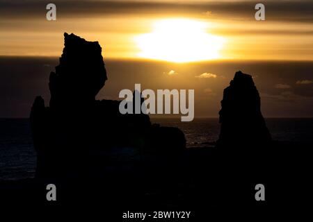 Sonnenuntergang am Meer in Island mit Felsen im Vordergrund Stockfoto