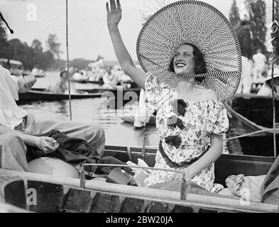 Mit der Hitzewelle als Ermutigung, Henley's Royal Regatta vied mit Ascot in der Vielfalt seiner Mode. Eine riesige Hutmode, die größte auf dem Fluss gesehen von einem Zuschauer getragen, die ihre Mannschaft zum Sieg von einem Punt entlang des Booms während des letzten Tages Rennen in Henley jubelte. Juli 1937 Stockfoto