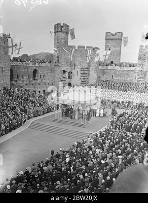 An der Stelle stehend, von der aus der Legende nach der erste Prinz von Wales den Häuptlingen gezeigt wurde, zeigten sich die König und Königin den Menschen von Wales am Ende ihrer zweitägigen Tour durch Wales im historischen Caernarvon Castle. Der König und die Königin hören einem Chor von 800. Mit ihren Majestäten ist Herr David Lloyd George, der Vollzugsbeamter des Schlosses. Der Hintergrund ist der Adlerturm. 15 Juli 1937. Stockfoto