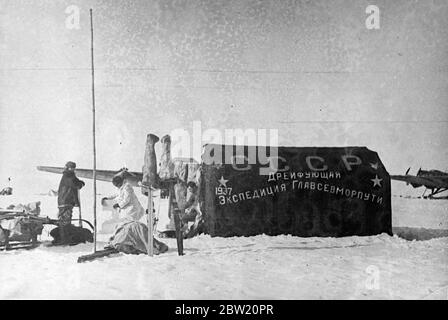 Diese Bilder, die ersten, die jemals am Nordpol gemacht wurden, wurden nach Moskau und von dort nach London geflogen. Der sowjetischen wissenschaftlichen Expedition unter Leitung von Professor Otto Schmidt ist es gelungen, sich auf einer Eisscholle in der gefrorenen Wildnis zu etablieren, aus der nun erstmals in der Geschichte wertvolle wissenschaftliche Informationen und regelmäßige Wetterberichte per Funk gesendet werden. Das Hauptzelt der Expedition mit der Inschrift: UdSSR, die Drifting Expedition der Hauptverwaltung der Nordseestreute -1937. 28 Juni 1937 Stockfoto