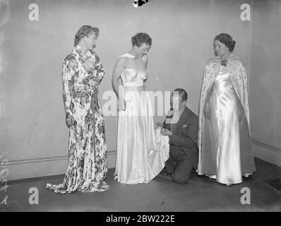 Ein Student, der die Kleider auf Modellen für die Anzeige anordnet.. Exquisite Kleider, die von ehemaligen und gegenwärtigen Studenten entworfen wurden, werden auf der dritten jährlichen Ausstellung des British Institute of Dress Designers in Piccadilly, London, gezeigt. Oktober 1937. Stockfoto