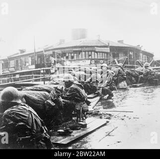 Japanische Marineinfanteristen hinter Stacheldraht und Sandsack-Barrikaden in Shanghai landeten Verstärkungen. Obwohl das nasse Wetter den Vormarsch hält, haben die Japaner 20,000 Marineinfanteristen und Truppen bei Woosung IS Verstärkungen in der Shanghai-Offensive gelandet. Foto zeigt, japanische Marineinfanteristen kauern hinter Samberg und Stacheldrahtzauben im Regen an einem der Bäche von Shanghai. Bild direkt aus China erhalten. 28. September 1937 Stockfoto