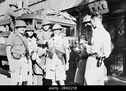 Amerikanische Mitglieder des Shanghai Volunteer Corps, als sie chinesische Zivilisten aus dem Schlachtfeld im Bezirk Yangtsepo [Bezirk Yangpu] evakuierten. Ein Baby wurde in ihrem Lastwagen geboren, als es auf dem Weg zur internationalen Siedlung war. Rechts ist ein amerikanischer Fotograf R. R. Brandt. 21. September 1937 Stockfoto