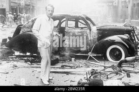 Dieses Bild, das gerade in London aus Shanghai aufgenommen wurde, zeigt John R. Morris, den Korrespondenten der United Press, der an der Nanking Road zwischen Cathay und Palace Hotels neben einem zerstörten Auto steht, kurz nachdem mehrere Bomben abgelassen wurden, 140 getötet und 40 Menschen verletzt wurden. Die Bomben wurden auf der Nanking Road abgesetzt, nachdem Flugzeuge die japanische Anbetung Idzumo angegriffen hatten. Ein gewaltiger Krater blieb zurück und etwa 20 Autos wurden komplett ausgebrannt. Zwei ausländische Autofahrer wurden gefangen und lebendig verbrannt. September 1937 Stockfoto