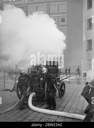 Alte und neue Methoden der Brandbekämpfung demonstrierte die Londoner Feuerwehr in einer Vorzeige vor dem Feuerwehrchef aus allen Teilen Englands im Brigadehauptsitz in London. Für die Anzeige wurden Feuergeräte vergangener Jahrhunderte und die aktuellste Ausrüstung verwendet. Feuerwehrmann war ein alter Pferdemotor, der während der Ausstellung ein Feuer kämpfte. 13. Oktober 1937. Stockfoto