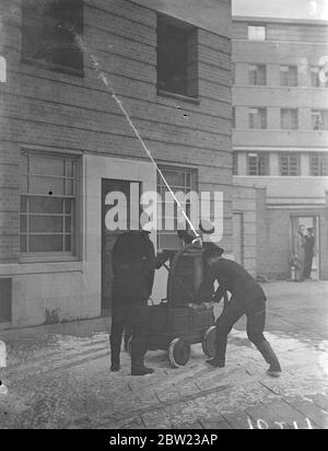 Alte und neue Methoden der Brandbekämpfung demonstrierte die Londoner Feuerwehr in einer Vorzeige vor dem Feuerwehrchef aus allen Teilen Englands im Brigadehauptsitz in London. Für die Anzeige wurden Feuergeräte vergangener Jahrhunderte und die aktuellste Ausrüstung verwendet. Feuerwehrleute arbeiten an einer alten manuellen Pumpe aus dem 18. Jahrhundert, um einen Brand zu unterdrücken. 13. Oktober 1937 Stockfoto