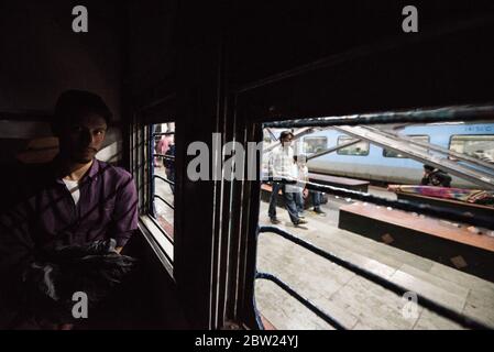 Mann, der aus dem Fenster des fahrenden Zuges der zweiten Klasse schaut. Indian Railways. Indien. Stockfoto
