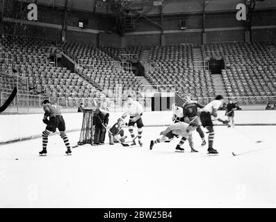 Englands Eishockeymannschaft für Weltmeisterschaften hat ein Trial Match in Harringay. Die englische Eishockeymannschaft, die gegen Ende nächsten Monats bei den Weltmeisterschaften in Prag antreten wird, hatte ein Trial Match in der Harringay Arena mit den Harringay Greyhounds, die für ihre starken Verteidigungslinien bekannt sind. Foto zeigt Jimmy Foster, der zum dritten Mal in Folge als Torhüter für England ausgewählt wurde, auf dem Eis, als er beim Testspiel einen Save machte. In Weiß rechts vom Netz ist M Colledge (Marlboroughs), ganz links J Rudley (Red Wings), hinter einem Mann mit 'Harringay' Trikot ist G Stockfoto