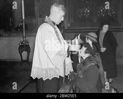 Segnung der Kehlen Zeremoniell in London Kirche am Fest der St. Blaise. Die Zeremonie der Kehlsegenszeremonie fand nach der Messe am Fest des hl. Blasius in der römisch-katholischen Kirche des hl. Ethelreda, Ely Place, im Zirkus Holborn, statt. Foto zeigt, Pater Baines, der Priester, segnet die Kehlen mit zwei brennenden Kerzen. Februar 1938 Stockfoto