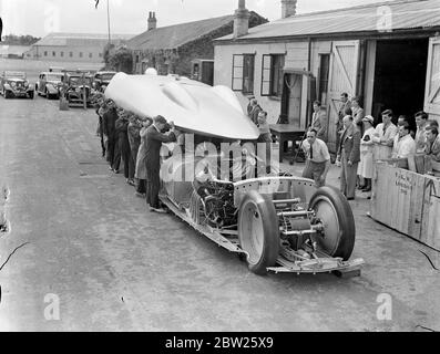 Cobbs neues Auto in Brooklands vor der Reise nach Amerika. Das Railton-Auto, in dem John Cobb Ende August in den Utah Salt Flats einen Versuch zum Weltrekord auf dem Land machen soll, war in seiner fertigen Form erstmals in Brooklands zu sehen, bevor es nach Amerika abging. Das Auto ist mit 1,250 PS Motoren ausgestattet. Cobbs Cockpit befindet sich vor der Achse in der Nase des Autos. Foto zeigt, dass die Karosserie auf dem Fahrgestell des Autos abgesenkt wird. Dieser leichte Körper muss angehoben werden, damit eine Einstellung vorgenommen werden kann. Juli 1938 Stockfoto