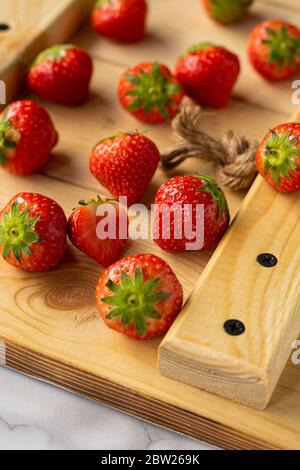 Selektiver Fokus, Beeren von reifen, selbstangebauten Erdbeeren mit grünen Blättern Stockfoto
