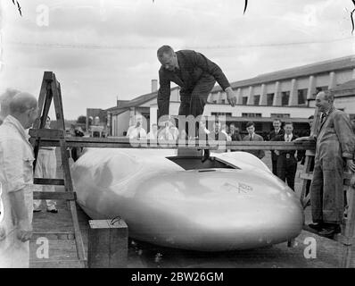 Cobbs neues Auto in Brooklands vor der Reise nach Amerika. Das Railton-Auto, in dem John Cobb Ende August in den Utah Salt Flats einen Versuch zum Weltrekord auf dem Land machen soll, war in seiner fertigen Form erstmals in Brooklands zu sehen, bevor es nach Amerika abging. Das Auto ist mit 1,250 PS Motoren ausgestattet. Cobbs Cockpit befindet sich vor der Achse in der Nase des Autos. Foto zeigt, John Cobb klettert ins Cockpit. Juli 1938 Stockfoto