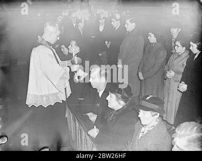 Segnung der Kehlen Zeremoniell in London Kirche am Fest der St. Blaise. Die Zeremonie der Kehlsegenszeremonie fand nach der Messe am Fest des hl. Blasius in der römisch-katholischen Kirche des hl. Ethelreda, Ely Place, im Zirkus Holborn, statt. Foto zeigt, Pater Baines, der Priester, segnet die Kehlen mit zwei brennenden Kerzen. Februar 1938 Stockfoto