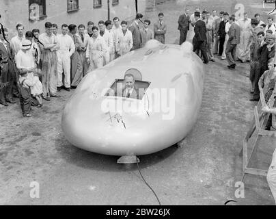 Cobbs neues Auto in Brooklands vor der Reise nach Amerika. Das Railton-Auto, in dem John Cobb Ende August in den Utah Salt Flats einen Versuch zum Weltrekord auf dem Land machen soll, war in seiner fertigen Form erstmals in Brooklands zu sehen, bevor es nach Amerika abging. Das Auto ist mit 1,250 PS Motoren ausgestattet. Cobbs Cockpit befindet sich vor der Achse in der Nase des Autos. Foto zeigt, John Cobb im Cockpit seines neuen Autos in brooklands, von Mechanikern beobachtet.. Juli 1938 Stockfoto