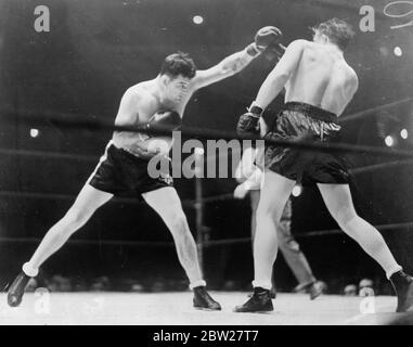 Tommy Farr verliert auf Punkte zu James Braddock, weigert sich, die Hände zu schütteln. Tommy Farr, britischer Empire-Champion, wurde im Madison Square Garden, New York, von James J Braddock, dem ehemaligen Schwergewichtsweltmeister, in 10 Runden punktegeschlagen. Enttäuscht über das Urteil, weigerte sich Far, die Hände zu schütteln, drehte Braddock den Rücken zu, trat über den Eimer in seiner Ecke und verließ den Ring. Später entschuldigte er sich. Foto zeigt, Tommy Farr (rechts) verlässt in der ersten Runde eine Linke von Braddock. 27. Januar 1938 Stockfoto