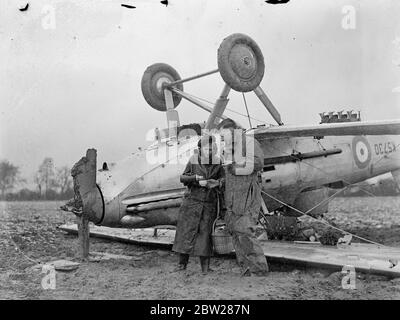 RAF-Flugzeug stürzt in gepflügten Feld in der Nähe von Watford im Schneesturm. Und die Beobachter waren in einem königlichen Luftwaffenjäger Hawker Demon Mk I gefangen, der in Bedmond, nahe Watford, in einem Schneesturm zusammenbrach. Die Maschine landete auf dem Kopf mit laufendem Motor. Zwei Argumente wurden von Farmhände befreit und hatten das Glück, Verletzungen zu entgehen. Das Flugzeug war in einem schneebedeckten gepflügten Feld heruntergekommen und hatte Schäden am Gummi erlitten. Foto zeigt, dass der führende Flugzeugbauer Goodwin nach dem Absturz eine Tasse Tee von Miss Elsie Chamberlain von Hemel Hempstead empfangen hat. 10. Januar 1938 Stockfoto