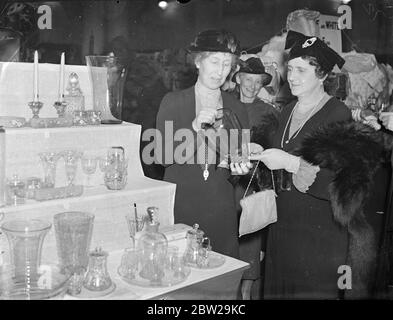 Marchioness of Willingdon eröffnet YMCA Bazaar. Die Marchioness of Willingdon eröffnet den jährlichen Basar der Young Woman's Christian Association in der Central Hall, Westminster, London. Foto zeigt, die Marchioness von Willingdon (rechts), die Glaswaren auf dem Stand der Lady Helen Graham, Präsidentin des Londoner YMCA und Lady in Waiting to the Queen. November 1937 Stockfoto