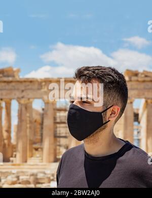 Athen Akropolis, Griechenland Coronavirus Tage. Junger Mann mit schützender Gesichtsmaske, altgriechischem Parthenon-Tempel und blauem Himmel-Hintergrund. Stockfoto