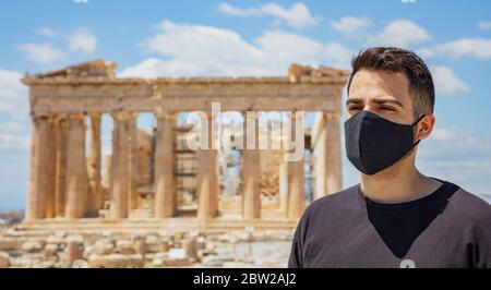 Athen Akropolis, Griechenland Coronavirus Tage. Junger Mann mit schützender Gesichtsmaske, altgriechischem Parthenon-Tempel und blauem Himmel-Hintergrund. Stockfoto