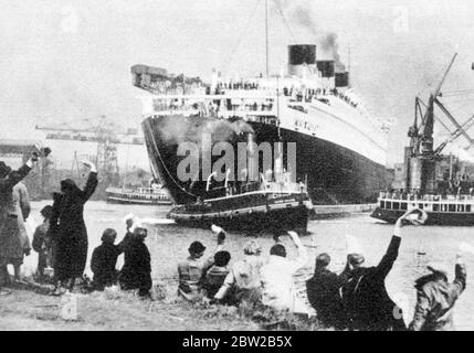 Die Leute winkten dem RMS Queen Mary zu und wurden von einem Schlepper gezogen. Stockfoto