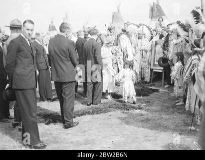 Originaltitel: Der König und die Königin besuchten ein Red Indian Lager in Calgary, Alberta, im Herzen des kanadischen Westens, am Fuße der Rocky Mountains. Der König und die Königin grüßen ein kleines indisches Kind - Papasse von indischen Häuptlingen und Squaws beobachtet, wie sie durch das Lager bewegt 5. Juni 1939 Stockfoto