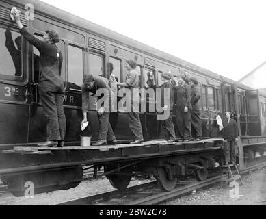 Frauen, die Schäuber und Reinigungskräfte auf der London und South Western Railway in Wimbledon reinigen einen Eisenbahnwaggon. 1917 Stockfoto