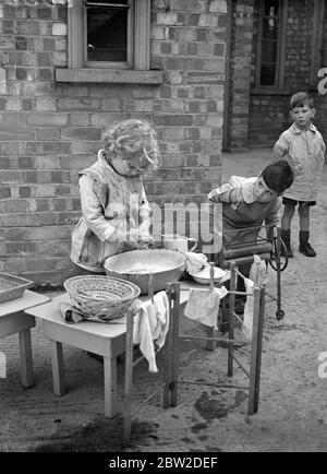 50 kleine Kinder unter fünf Jahren in der Romani-Kinderschule stellten den Schülern des Gypsy Hill Training College for Teachers of Young Children, Gypsy Hill, an dem es befestigt ist, Proben aus erster Hand zur Verfügung. Das College war das erste in Großbritannien, das die Ausbildung von Lehrern für Kindergärten. Kinder im Kindergarten können ein Baby baden, richtige Tischmanieren verwenden und kochen. Sie sollen am 10. November vor der Herzogin von Kent in der Stadt eine Ausstellung geben, um Geld für das College zu sammeln. Foto zeigt: Ein kleines Mädchen Schülerin der Kinderschule am Waschbottich. 14 Oktobes Stockfoto