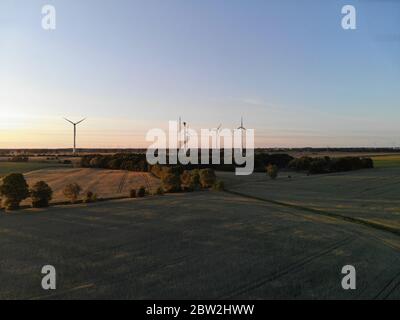 Luftaufnahme von Windenergieanlagen auf Weide im ländlichen Raum bei Sonnenuntergang Stockfoto