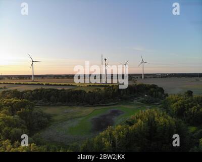 Luftaufnahme von Windenergieanlagen auf Weide im ländlichen Raum bei Sonnenuntergang Stockfoto